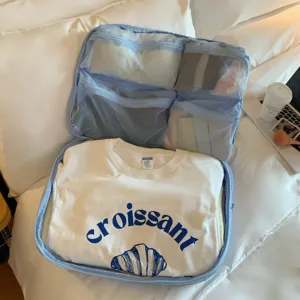 Bolsa organizadora de viaje azul claro abierta con bolsillos de malla para la ropa