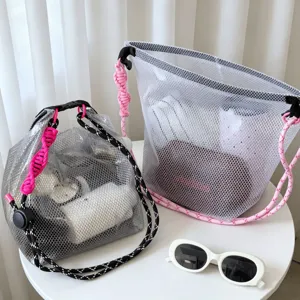 Two waterproof mesh beach bags with colorful braided rope handles on a white table