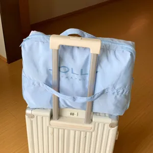 Detalle de una bolsa de viaje azul claro sujeta al asa de una maleta de equipaje