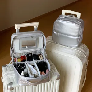Metallic silver PU makeup bag with mirror and compartments on white travel suitcases