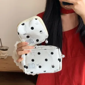 Close-up detail of white polka dot pouches featuring pearl zipper pulls and silver bows