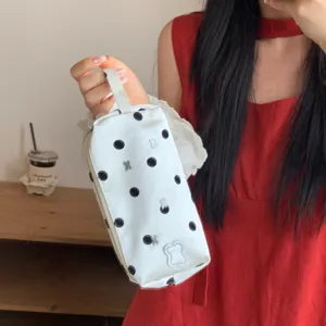Detailed view of a white polka dot pencil case with cute bear patches held by a person