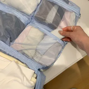 Detalle del organizatore de viaje de malla azul llenándose de ropa para la maleta