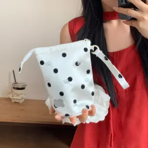 Detailed view of a white pencil case with black polka dots and butterfly embroidery.