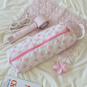 Detailed view of the quilted white storage bag for hair dryers with pink bow patterns