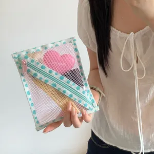 Handheld close-up van een blauw gestippelde mesh organizer tas met roze rits details