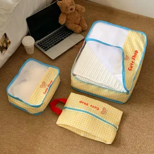 Detailed view of yellow checkered travel organizers with mesh panels and cute bear print