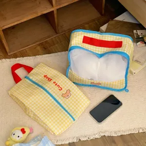 Close-up view of yellow gingham mesh travel storage bag with red handle and zipper detail