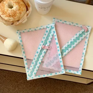 Detailopname van roze mesh opbergtassen met blauwe polkadots rand en ritsen