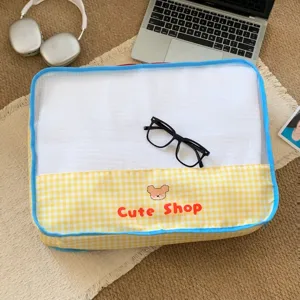 Close-up detail of mesh yellow gingham travel storage bag with cute cartoon bear print