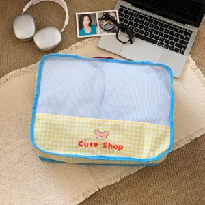 Lifestyle view of a yellow checkered mesh travel storage bag with a cute bear design