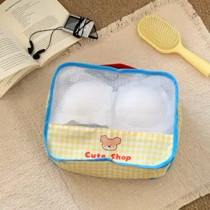 Close-up of yellow gingham mesh storage bag with cute bear and blue piping detail