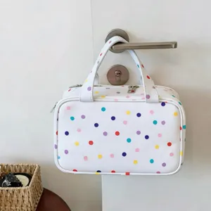 Detailansicht einer weißen Reise-Kulturtasche mit bunten Punkten, die an einer Tür hängt