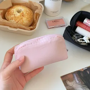 Handheld close-up of a small pink minimalist fabric lipstick pouch for daily storage