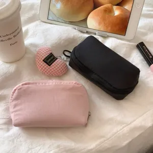 Lifestyle display of mini solid pink and black lipstick storage bags on a white fabric background