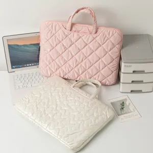Stylish quilted laptop sleeves in pink and cream shown in an office setting.