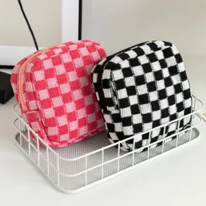 Gros plan de pochettes de rangement tricotées à damier dans un panier blanc