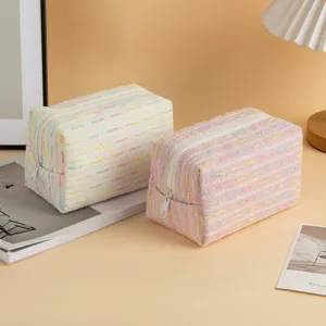 Dettaglio di borse per cosmetici a righe arcobaleno su una calda scrivania accogliente