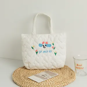 Detail of quilted white tote bag featuring cute dog embroidery and heart patterns