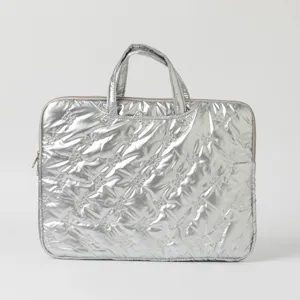 Detailed view of a silver metallic quilted laptop bag with decorative butterfly stitching