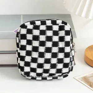 Gros plan d'une trousse de maquillage tissée avec motif en damier noir et blanc.
