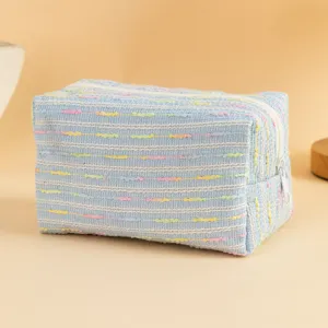 Vista dettagliata di una borsa cosmetica intrecciata blu con strisce arcobaleno e cerniera