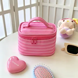 Detailansicht einer rosa gestreiften Kosmetiktasche auf einem Schminktisch.