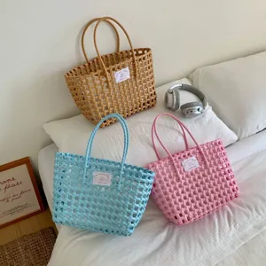 Detailansicht farbenfroher handgefertigter Korbtaschen in Pink, Blau und Braun auf einem Bett