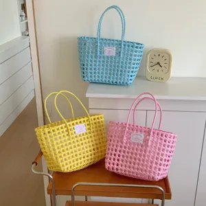 Detailansicht handgefertigter geflochtener Strandtaschen in Gelb, Blau und Rosa für den Sommer