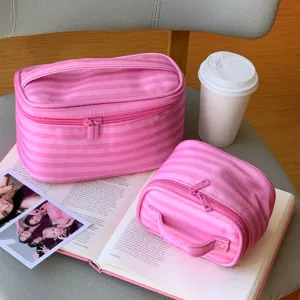 Detailansicht der hochwertigen großen und kleinen rosa gestreiften Kosmetiktaschen auf Buch