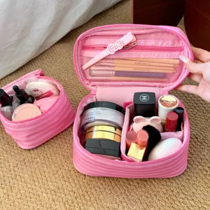 Innenansicht der rosa gestreiften Kosmetiktasche mit Fächern voll mit Make-up Produkten