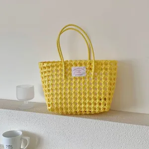 Detail der handgefertigten gelben Strandtasche auf einem weißen strukturierten Regal