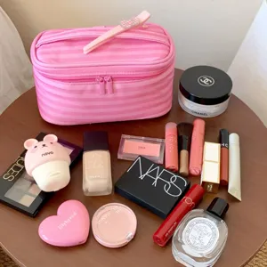 Große gestreifte Kosmetiktasche in Rosa mit Griff und verschiedenen Kosmetik-Requisiten