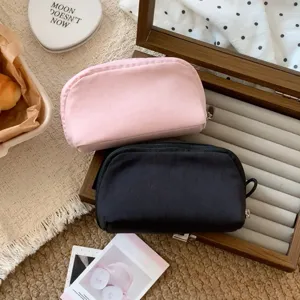 Two mini solid color makeup pouches in pink and black displayed on a jewelry box
