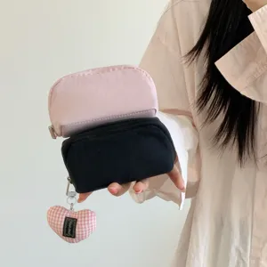 Close-up view of a person holding two mini solid color lipstick storage pouches in pink and black