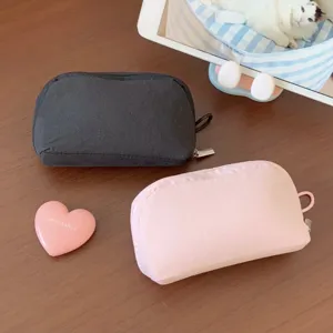 Top view of pink and black mini canvas cosmetic pouches on a wooden table
