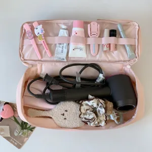 Detailed view of pink double-layer hair dryer storage bag with various beauty tools