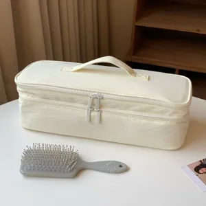 Lifestyle detail of a cream double-layer storage bag for hair dryers on a white table