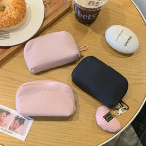 Close-up of three mini plain makeup pouches in pink and black on a cozy cafe table