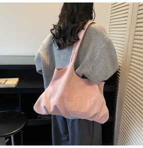 Gedetailleerd overzicht van een roze suède grote draagtas met logo gedragen door model