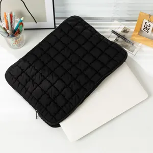 Detailansicht der schwarzen gesteppten Laptoptasche mit weicher Wolkenstruktur auf Tisch