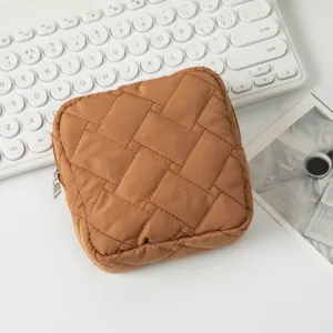 Detail einer braunen gesteppten Kosmetiktasche auf einem weißen Schreibtisch-Setup