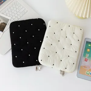 Detailed macro view of black and white polka dot embroidered tablet and laptop sleeves