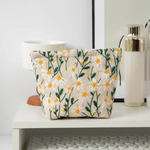 Detailansicht der bestickten Segeltuch-Kosmetiktasche mit Gänseblümchen auf weißem Tisch