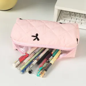 Close-up detail of a pink quilted pencil case with bow tie embroidery filled with pens