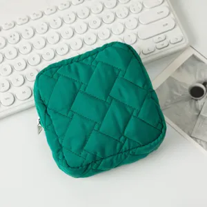 Detailansicht einer grünen gesteppten Kosmetiktasche auf weißem Schreibtisch