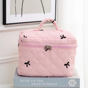 Detailed close-up showing the pink quilted fabric and black embroidered bows on the storage bag