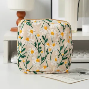 Nahaufnahme der Segeltuch-Kosmetiktasche mit feiner Gänseblümchen-Stickerei-Textur.