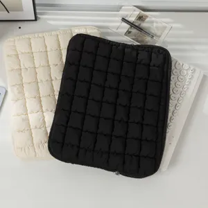 Detailansicht der gesteppten Laptoptaschen in Schwarz und Creme auf einem Schreibtisch