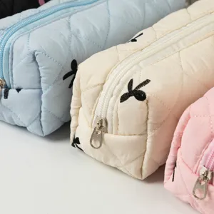 Close-up of quilted bow embroidery storage bags in multiple pastel colors with zippers.